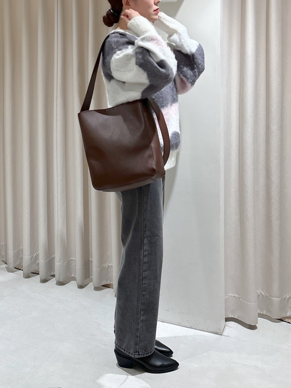 ホワイト系のニット/セーター、ブラウン系のトートバッグ、ブラック系のデニムパンツを着用したレディースの冬コーディネートの8枚目の写真