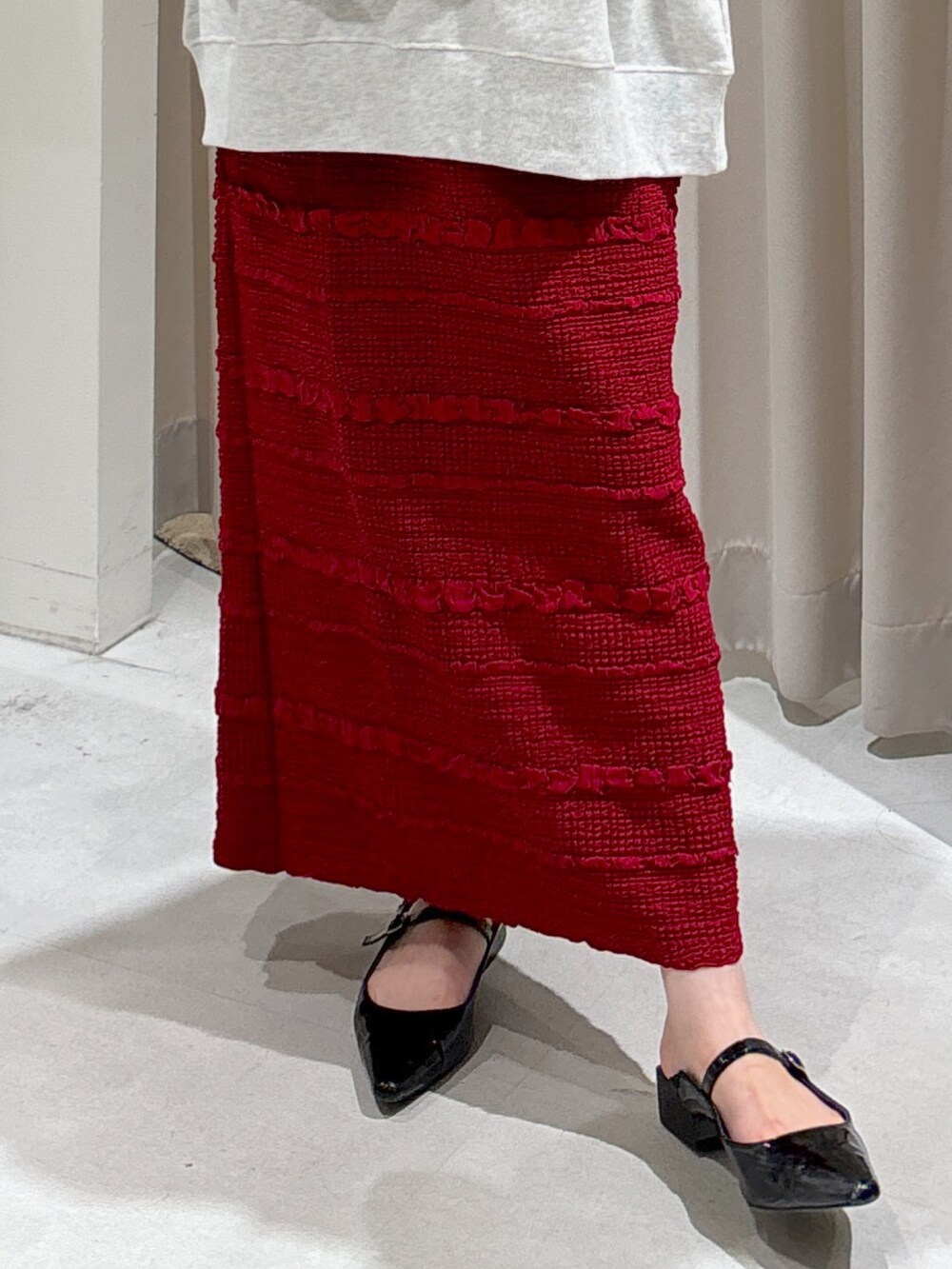 ホワイト系のスウェット、レッド系のスカート、ブラック系のパンプスを着用したレディースの秋コーディネートの4枚目の写真