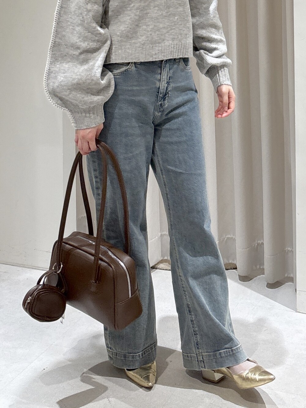 ブラウン系のステンカラーコート、ブルー系のトートバッグ、ブルー系のデニムパンツを着用したレディースの秋コーディネートの8枚目の写真