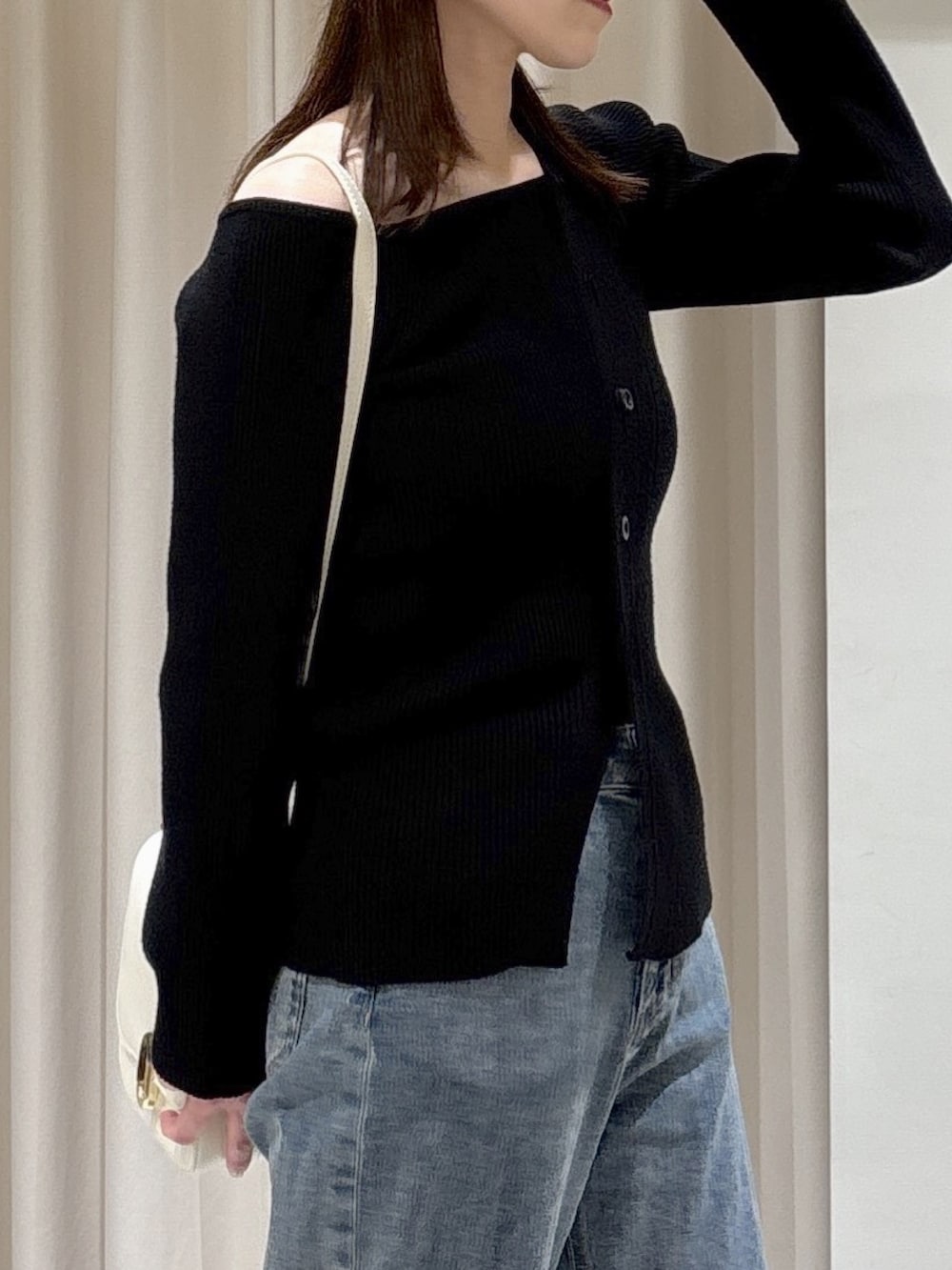 ブラック系のニット/セーター、ホワイト系のハンドバッグ、ブルー系のデニムパンツを着用したレディースの冬コーディネートの2枚目の写真