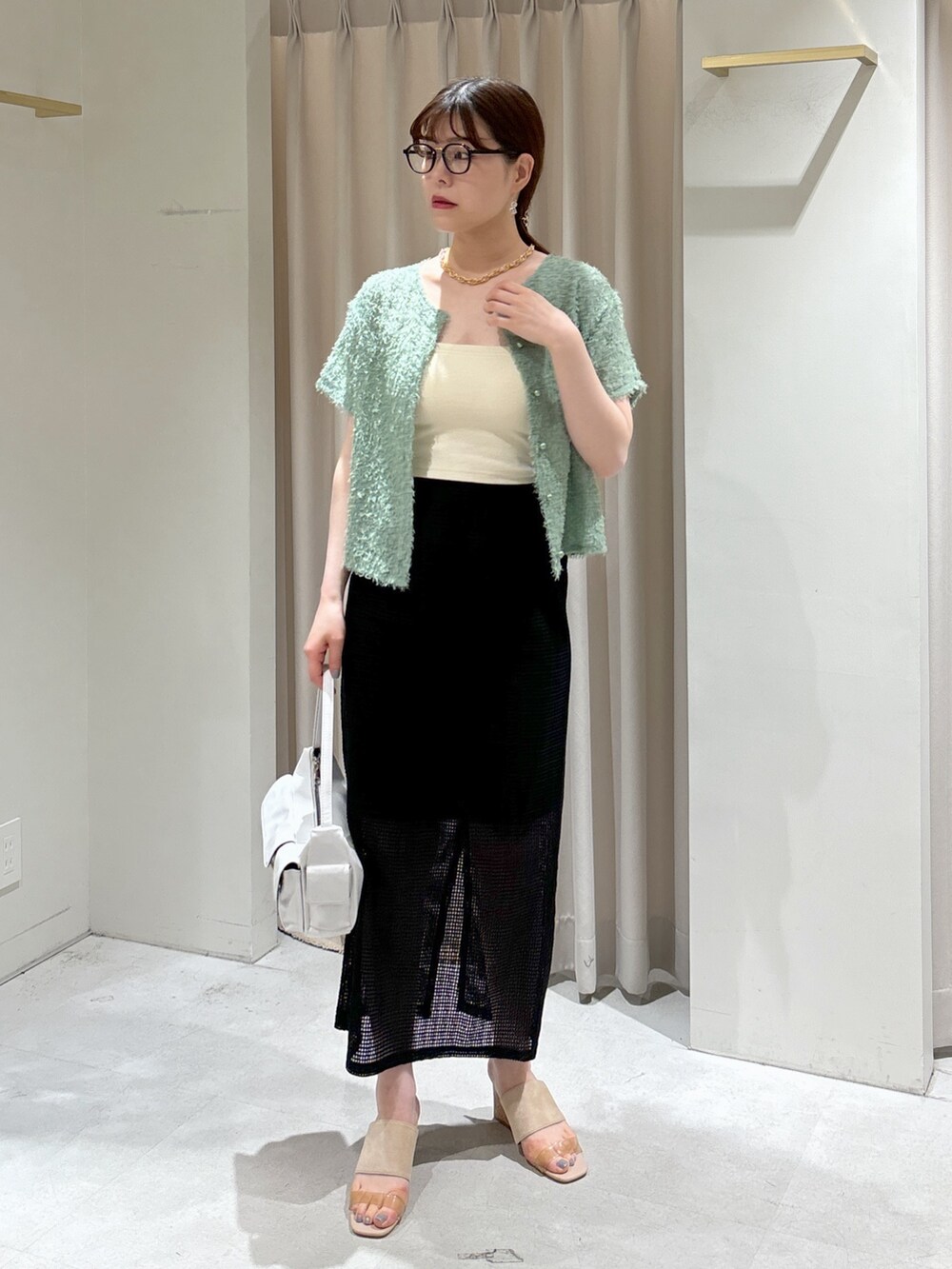 ブラック系のスカート、グレー系のサンダル、ホワイト系のハンドバッグを着用したレディースの夏コーディネートの3枚目の写真