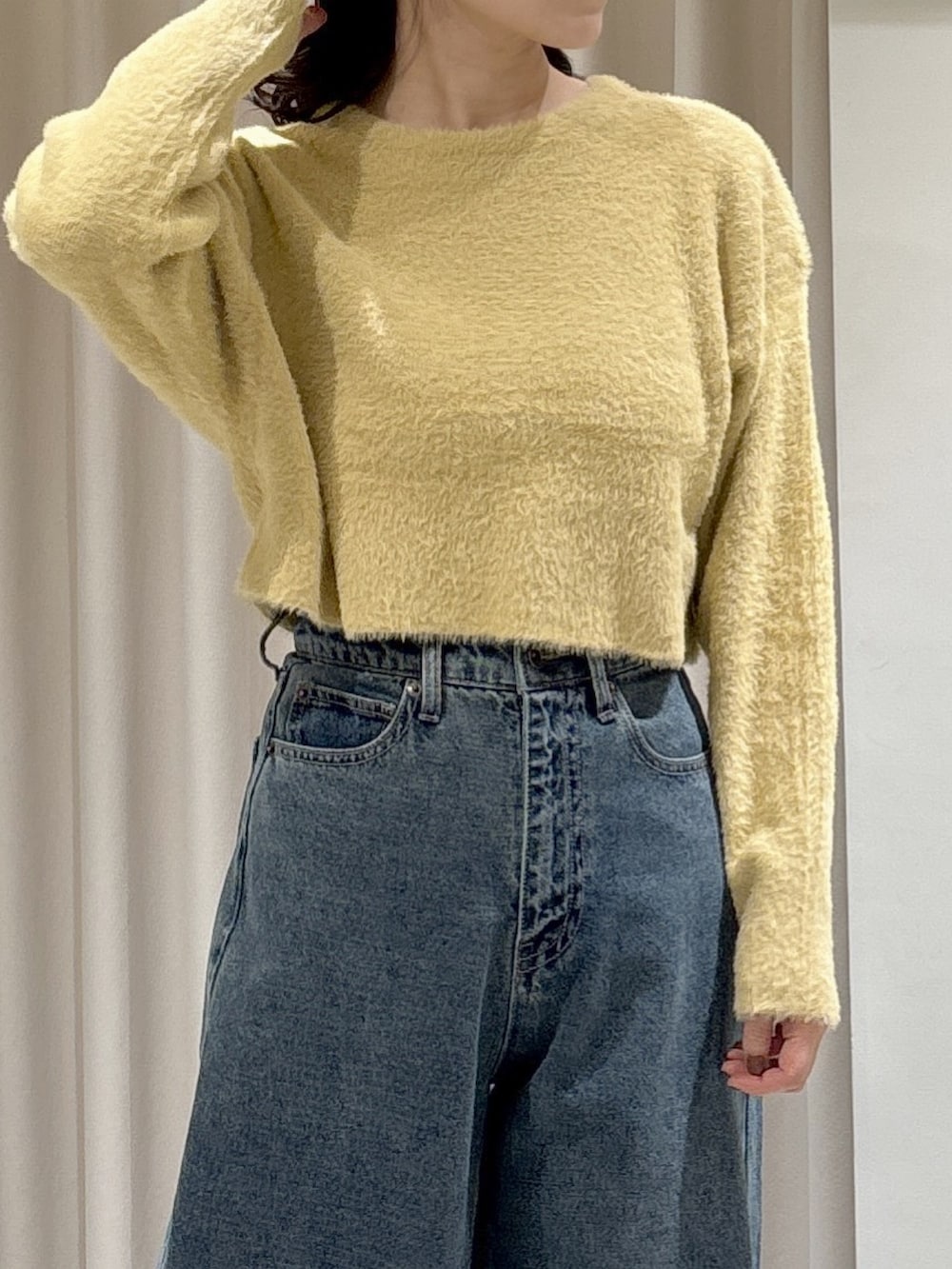 イエロー系のニット/セーター、ブラック系のトートバッグ、ブルー系のデニムパンツを着用したレディースの冬コーディネートの5枚目の写真