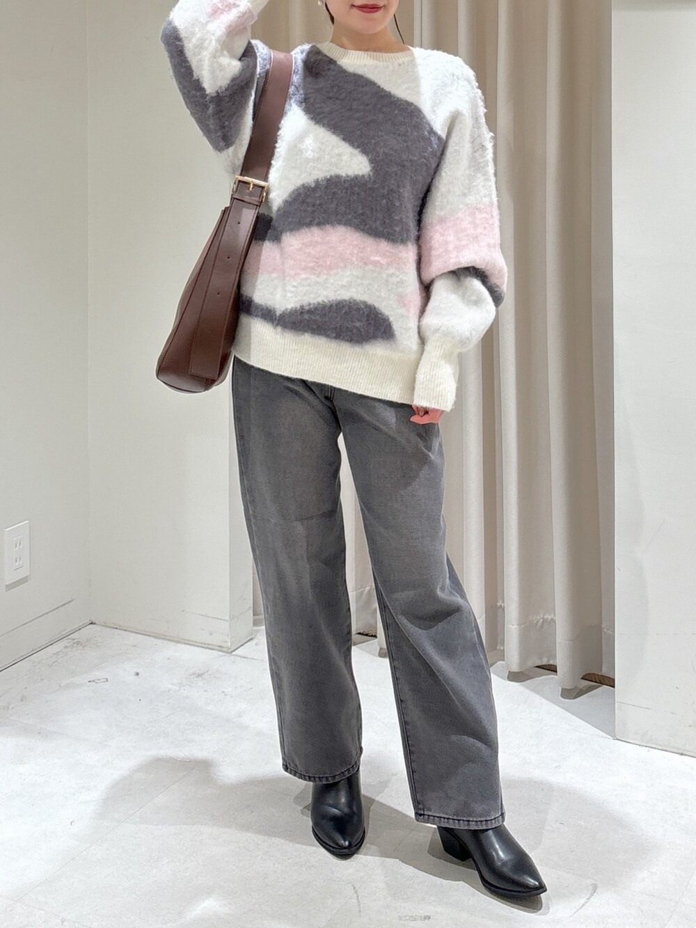 ホワイト系のニット/セーター、ブラウン系のトートバッグ、ブラック系のデニムパンツを着用したレディースの冬コーディネートの2枚目の写真