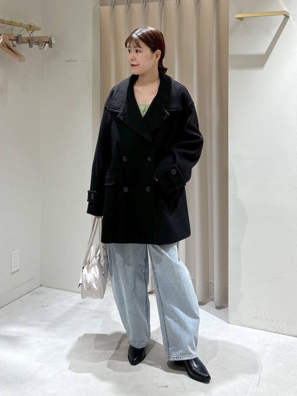 グリーン系のカーディガン/ボレロ、ブルー系のデニムパンツ、ブラック系のハンドバッグを着用したレディースの秋コーディネートの2枚目の写真