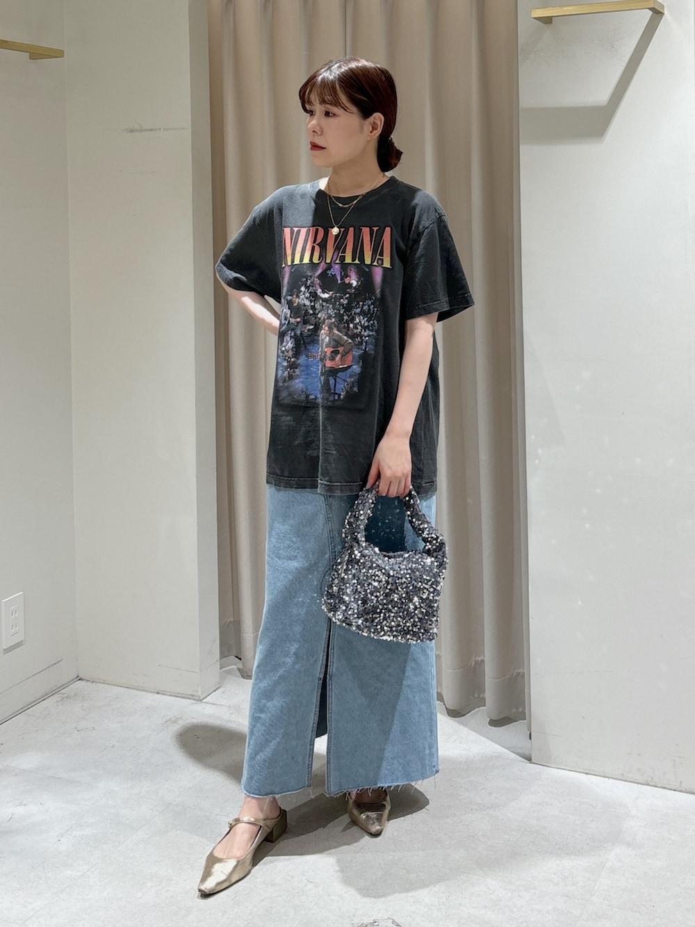 ブルー系のデニムスカート、ゴールド系のパンプス、ブラック系のTシャツ/カットソーを着用したレディースの春コーディネートの6枚目の写真