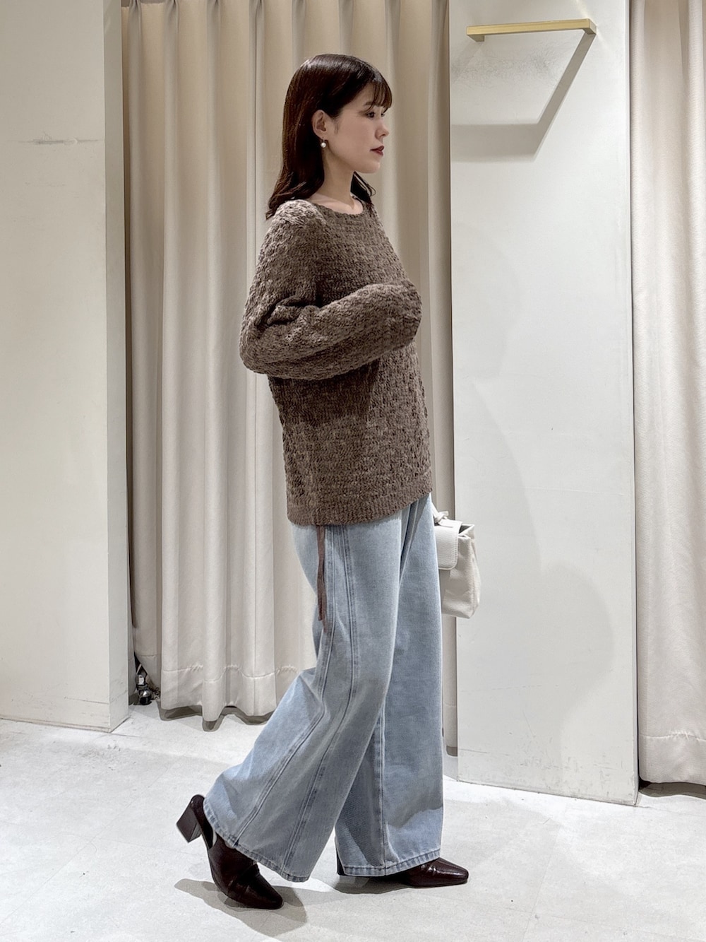 ブラウン系のニット/セーター、ホワイト系のショルダーバッグ、ブルー系のデニムパンツを着用したレディースの冬コーディネートの5枚目の写真