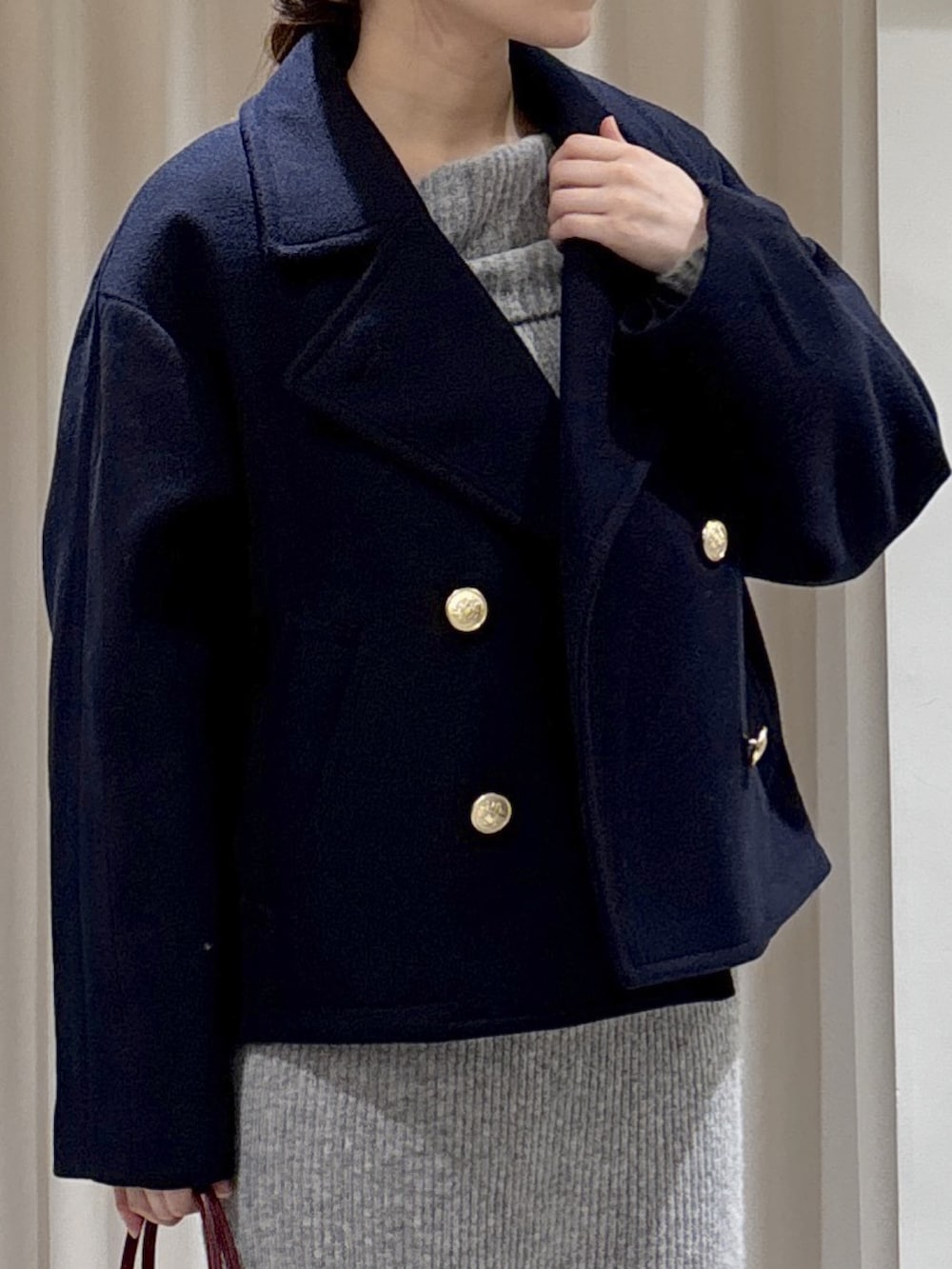 ブルー系のピーコート、レッド系のショルダーバッグ、グレー系のワンピースを着用したレディースの秋コーディネートの2枚目の写真