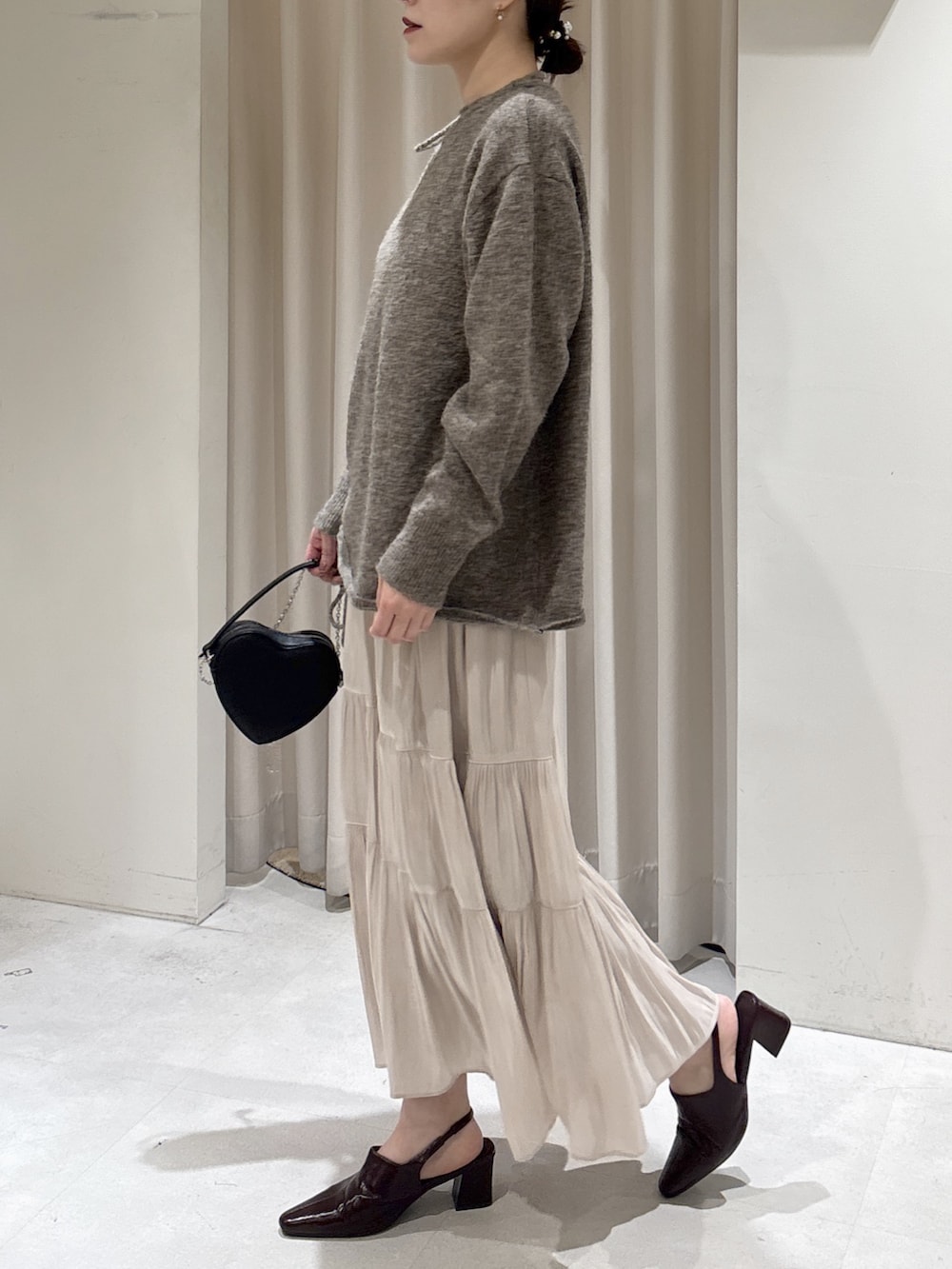 ブラウン系のニット/セーター、ホワイト系のスカート、ブラウン系のパンプスを着用したレディースの冬コーディネートの3枚目の写真