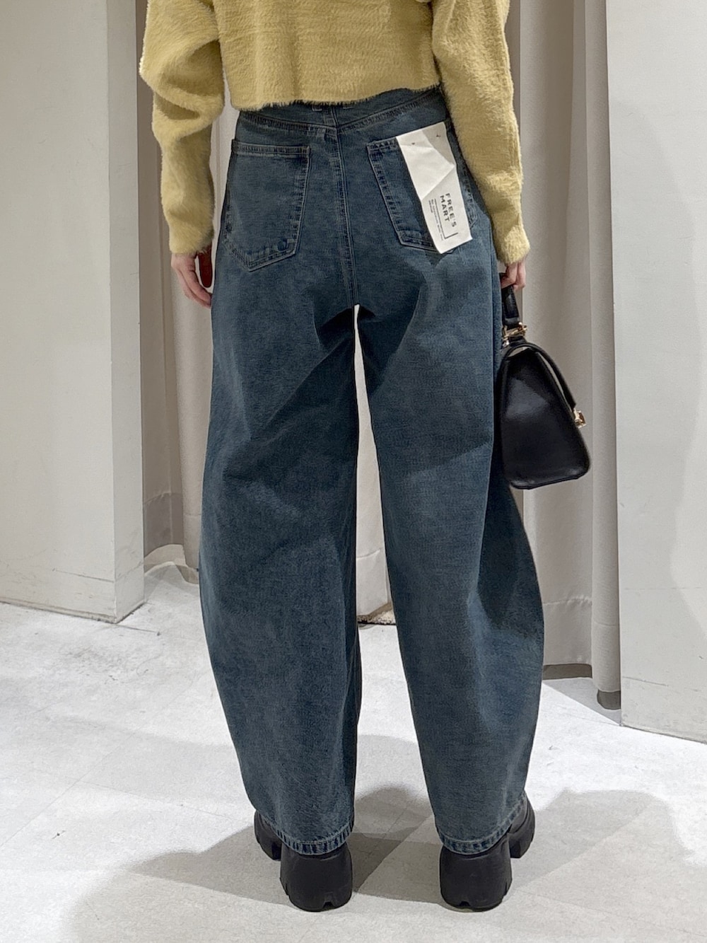 イエロー系のニット/セーター、ブラック系のトートバッグ、ブルー系のデニムパンツを着用したレディースの冬コーディネートの6枚目の写真