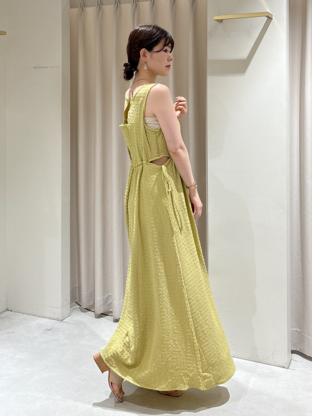 イエロー系のワンピース、ブラック系のショルダーバッグ、グレー系のサンダルを着用したレディースの夏コーディネートの4枚目の写真