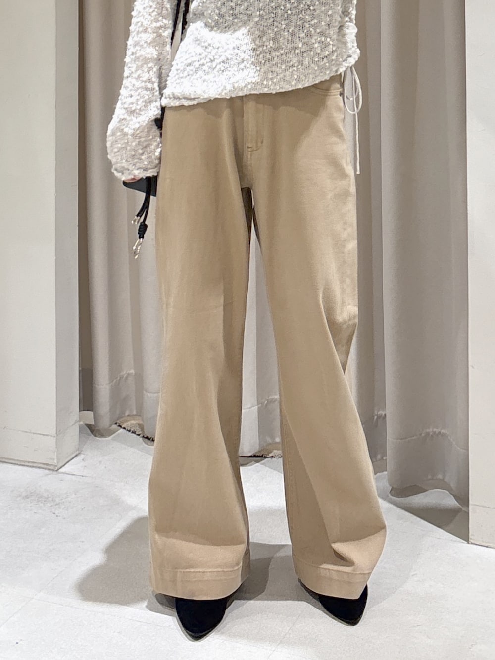 グレー系のニット/セーター、ブラック系のショルダーバッグ、ベージュ系のデニムパンツを着用したレディースの秋コーディネートの5枚目の写真