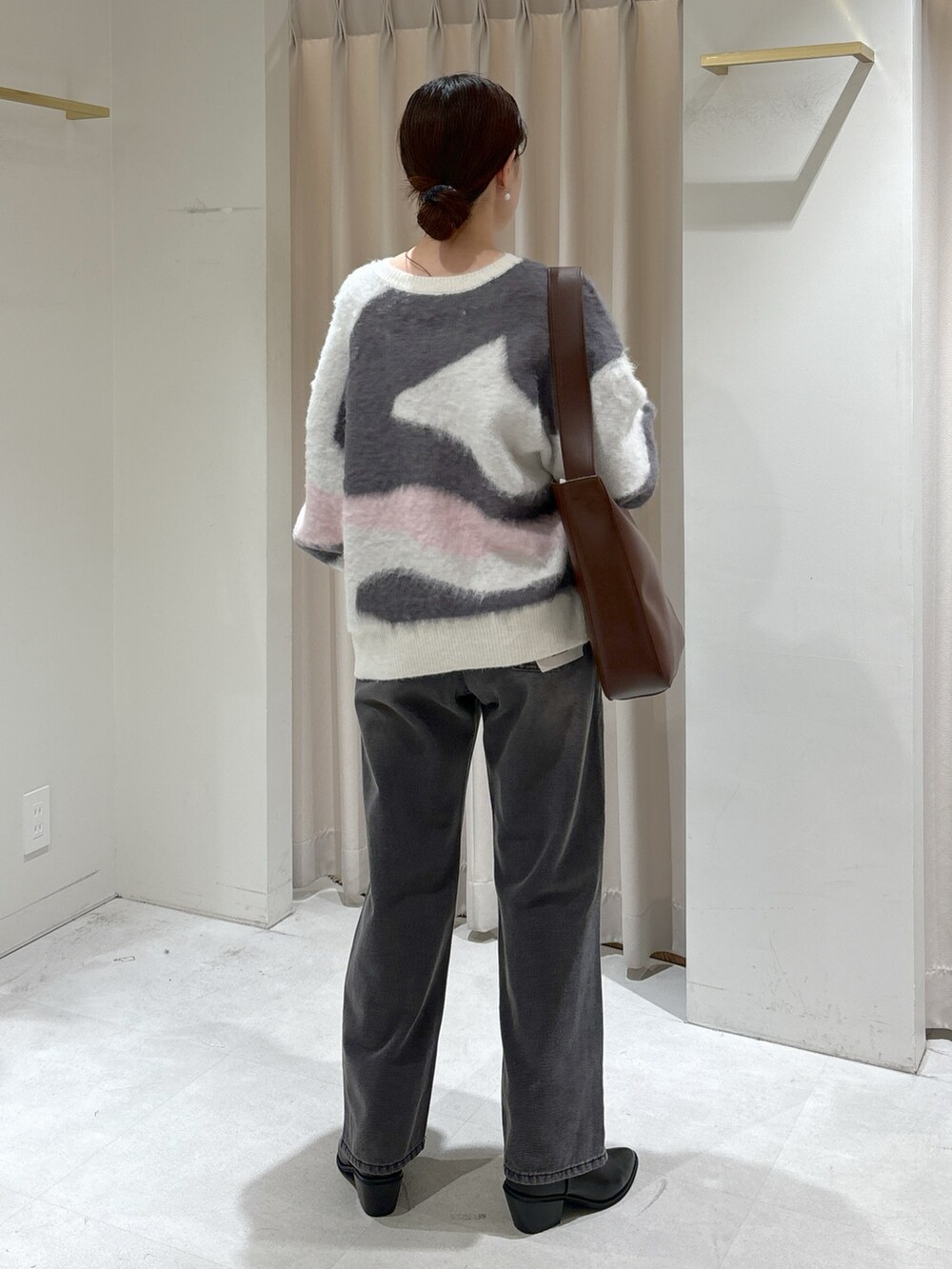 ホワイト系のニット/セーター、ブラウン系のトートバッグ、ブラック系のデニムパンツを着用したレディースの冬コーディネートの5枚目の写真