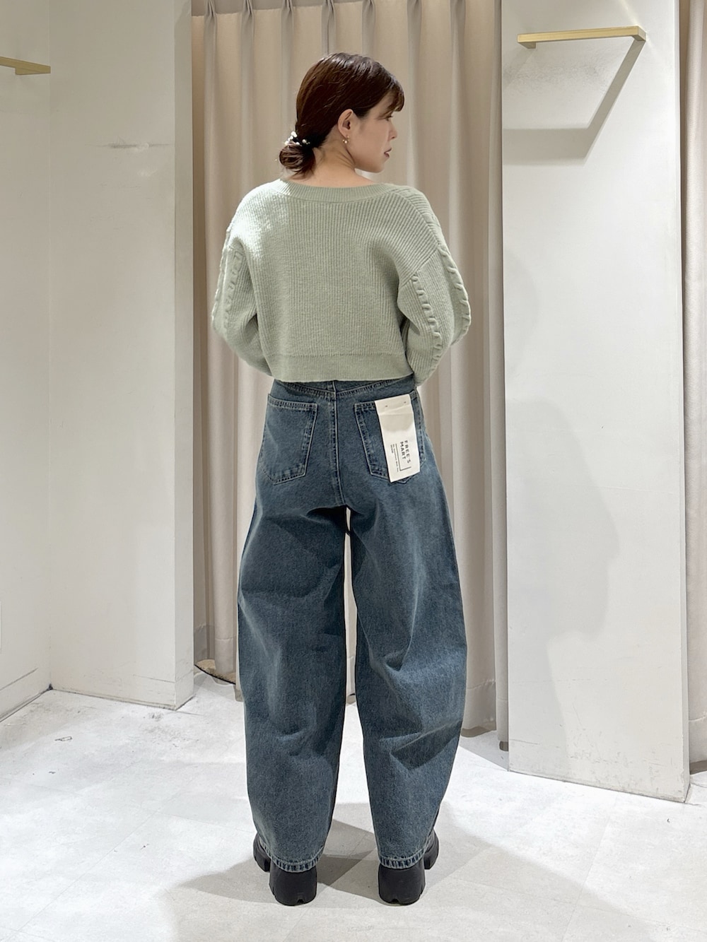 グリーン系のワンピース、ブルー系のデニムパンツ、ブラック系のトートバッグを着用したレディースの冬コーディネートの6枚目の写真