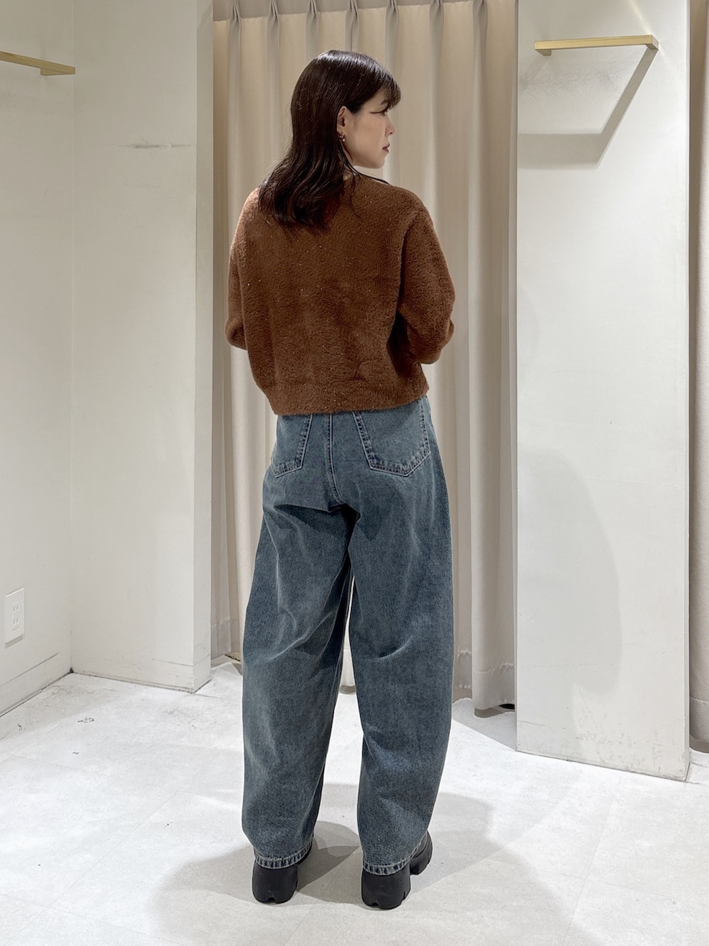 ブラウン系のニット/セーター、ブラック系のハンドバッグ、ブルー系のデニムパンツを着用したレディースの冬コーディネートの4枚目の写真