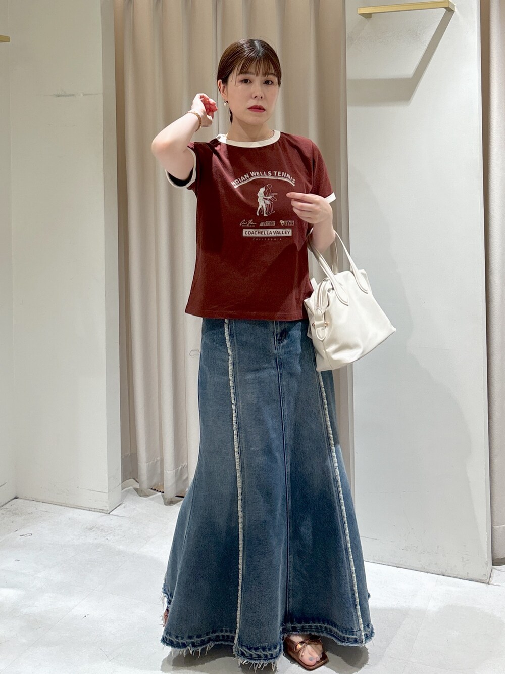 ブラウン系のTシャツ/カットソー、ホワイト系のボストンバッグ、ブルー系のスカートを着用したレディースの夏コーディネートの2枚目の写真