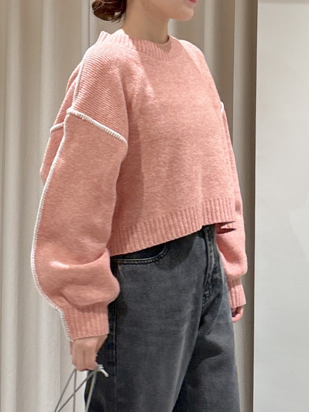 ピンク系のニット/セーター、ブラック系のデニムパンツ、グレー系のハンドバッグを着用したレディースの秋コーディネートの3枚目の写真