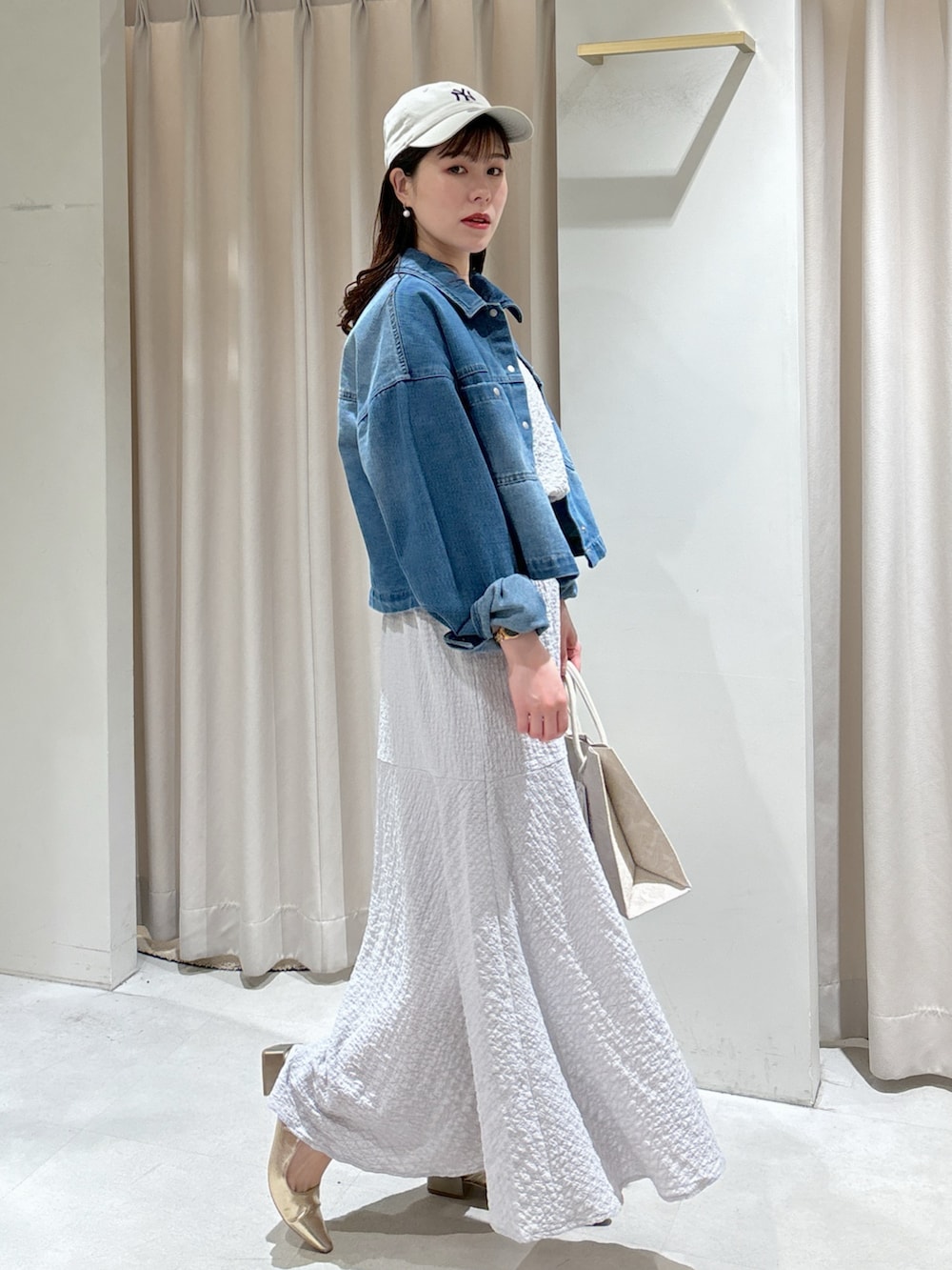 グレー系のワンピース、ホワイト系のトートバッグ、ゴールド系のパンプスを着用したレディースの春コーディネートの5枚目の写真