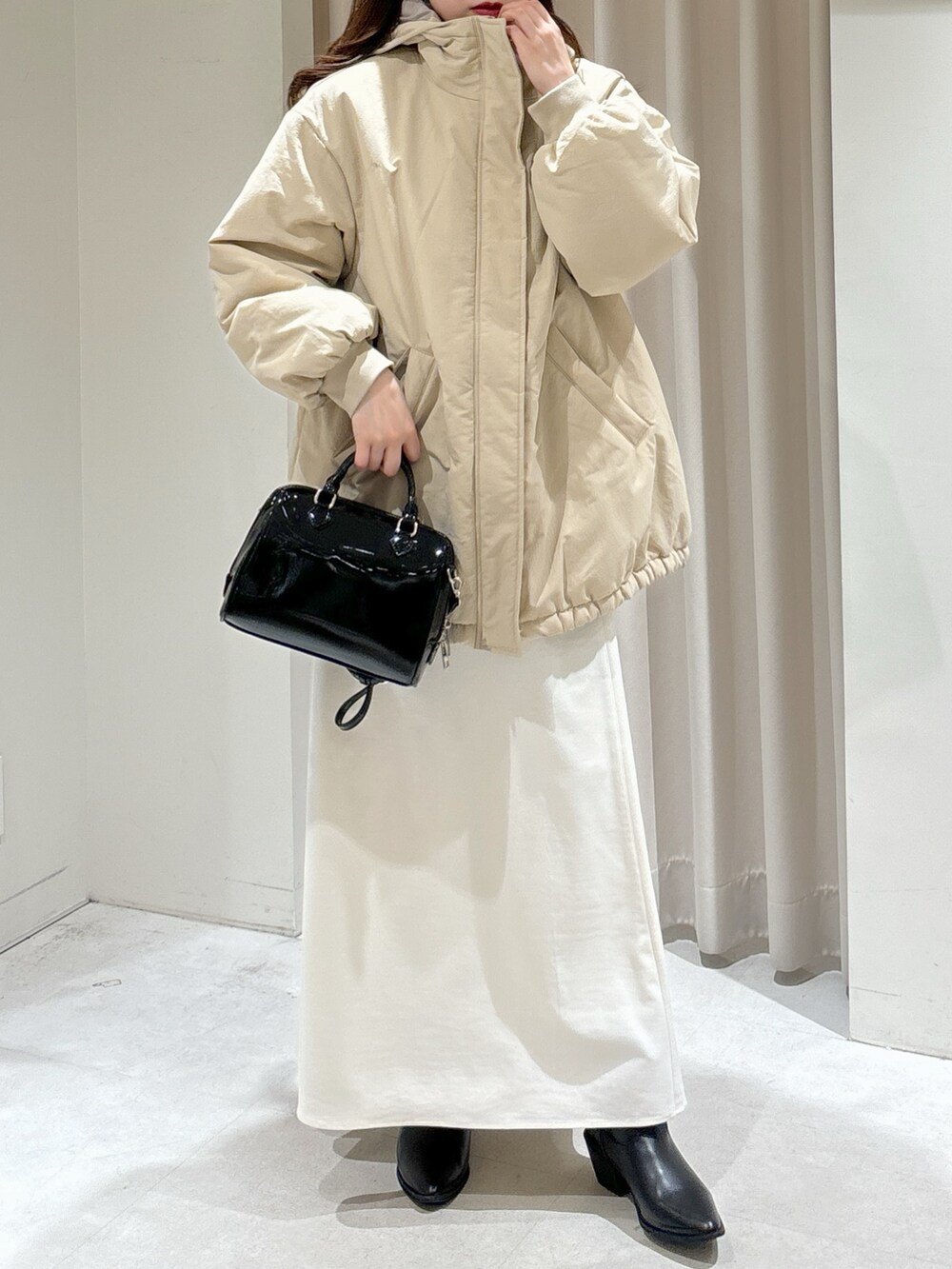 ベージュ系のブルゾン、ブラック系のショルダーバッグ、ホワイト系のスカートを着用したレディースの冬コーディネートの7枚目の写真