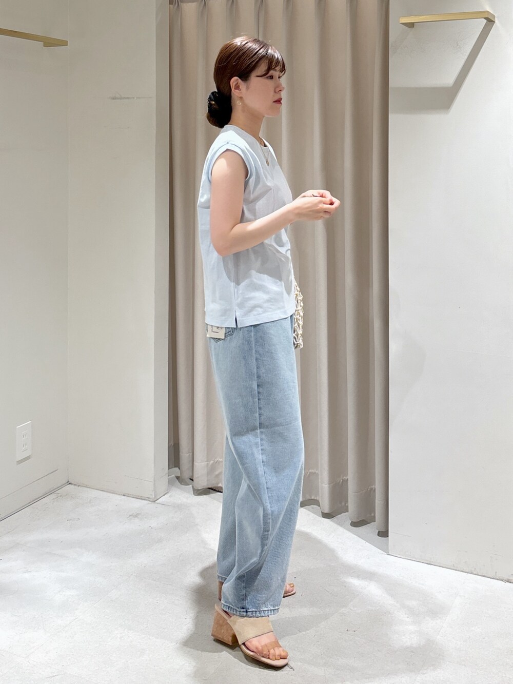 ブルー系のTシャツ/カットソー、ブルー系のデニムパンツ、ホワイト系のハンドバッグを着用したレディースの春コーディネートの6枚目の写真