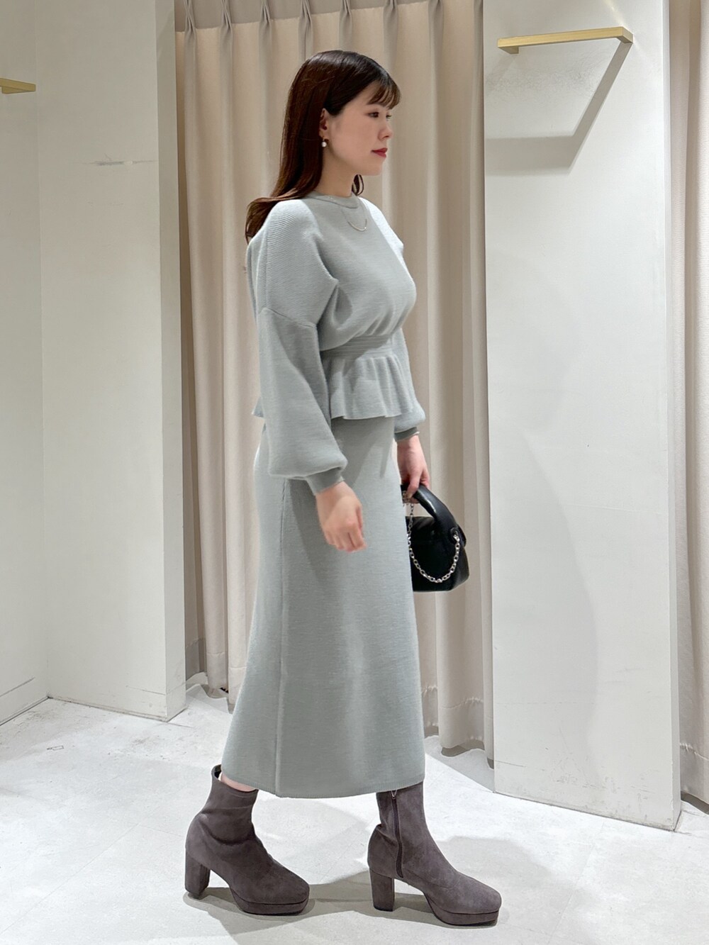 グリーン系のワンピース、ブラック系のショルダーバッグ、グレー系のブーツを着用したレディースの冬コーディネートの4枚目の写真