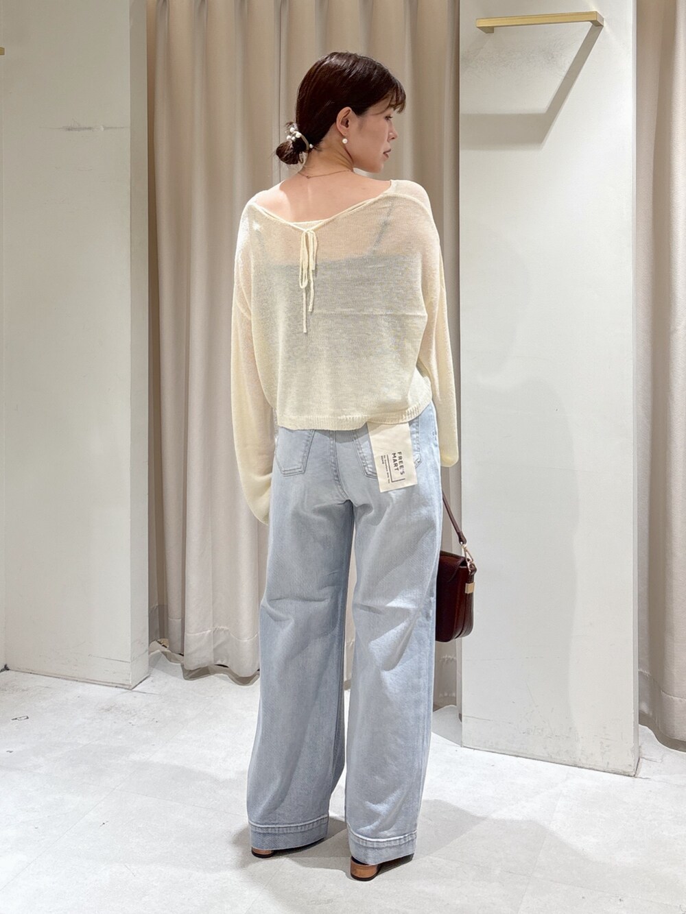 ブラウン系のハンドバッグ、ホワイト系のニット/セーター、ブラック系のキャミソールを着用したレディースの秋コーディネートの3枚目の写真