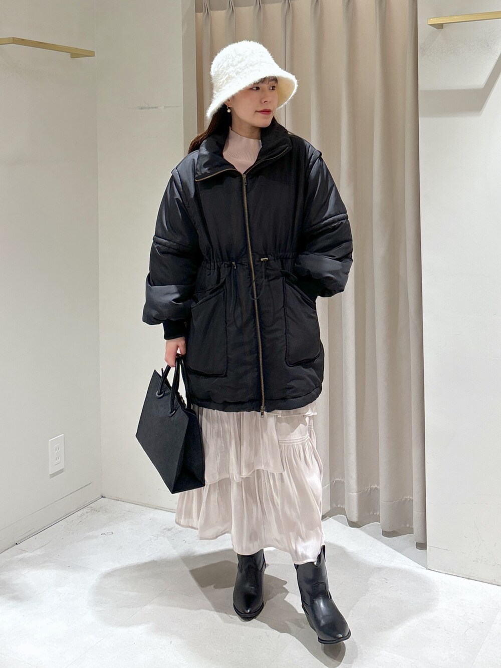 ブラック系のトートバッグ、ホワイト系のスカート、ブラック系のブーツを着用したレディースの冬コーディネートの4枚目の写真