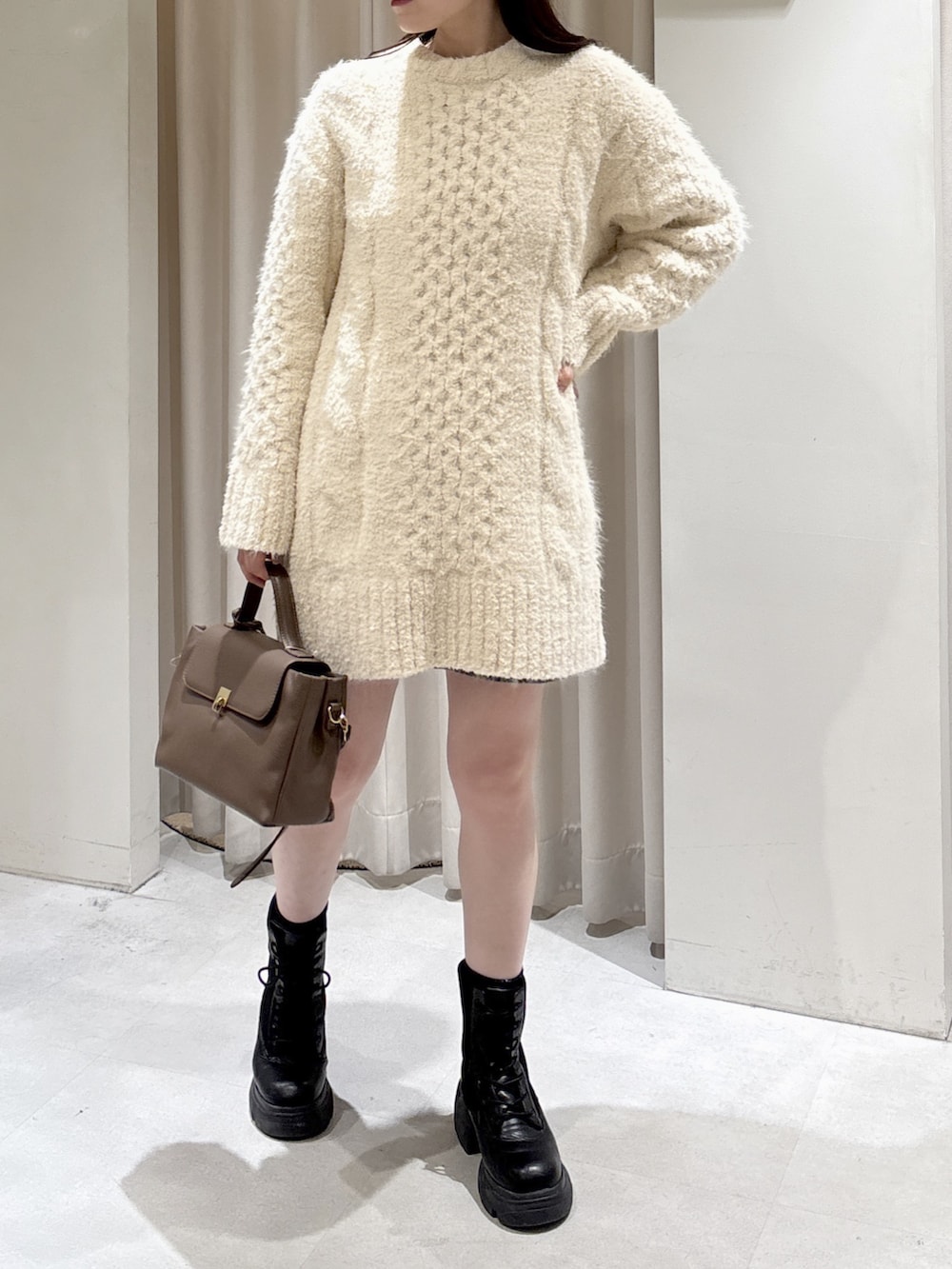 ホワイト系のワンピース、ブラウン系のショルダーバッグ、ブラウン系のスカートを着用したレディースの冬コーディネートの2枚目の写真