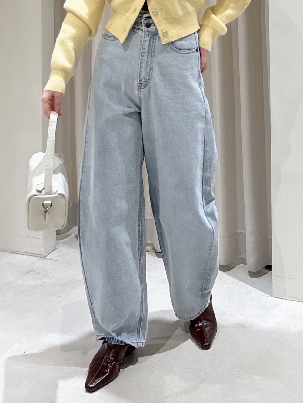 イエロー系のニット/セーター、ブラウン系のパンプス、ブルー系のデニムパンツを着用したレディースの冬コーディネートの4枚目の写真