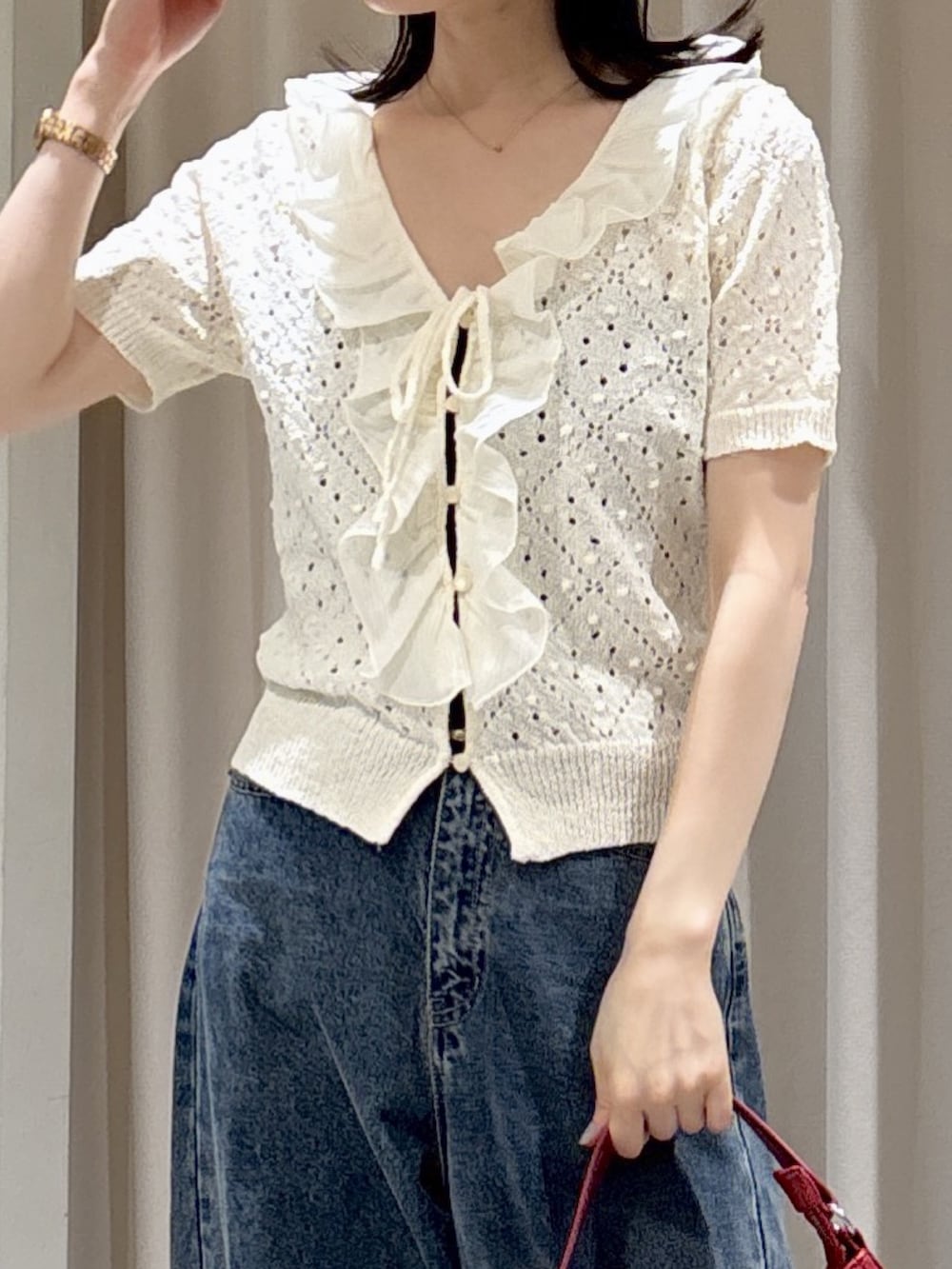 ホワイト系のニット/セーター、レッド系のショルダーバッグ、ブルー系のデニムパンツを着用したレディースの夏コーディネートの3枚目の写真