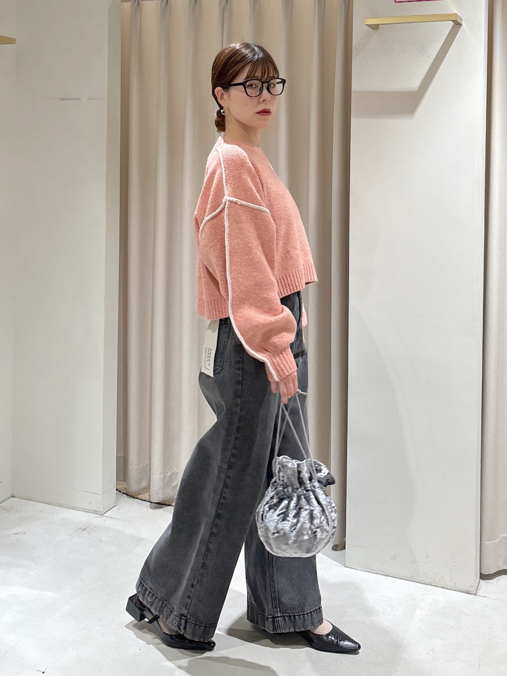 ピンク系のニット/セーター、ブラック系のデニムパンツ、グレー系のハンドバッグを着用したレディースの秋コーディネートの5枚目の写真