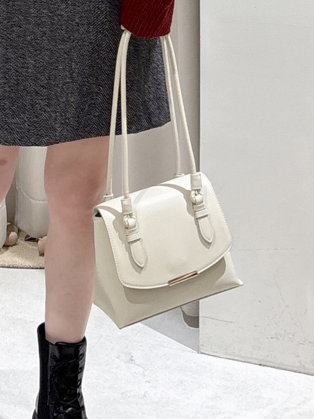 レッド系のニット/セーター、ホワイト系のショルダーバッグ、ブラック系のスカートを着用したレディースの冬コーディネートの6枚目の写真