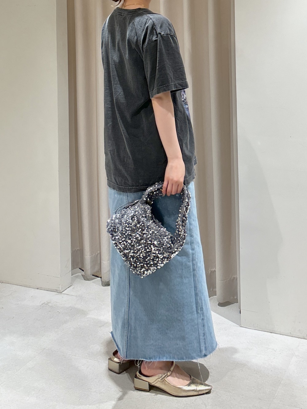 ブルー系のデニムスカート、ゴールド系のパンプス、ブラック系のTシャツ/カットソーを着用したレディースの春コーディネートの7枚目の写真