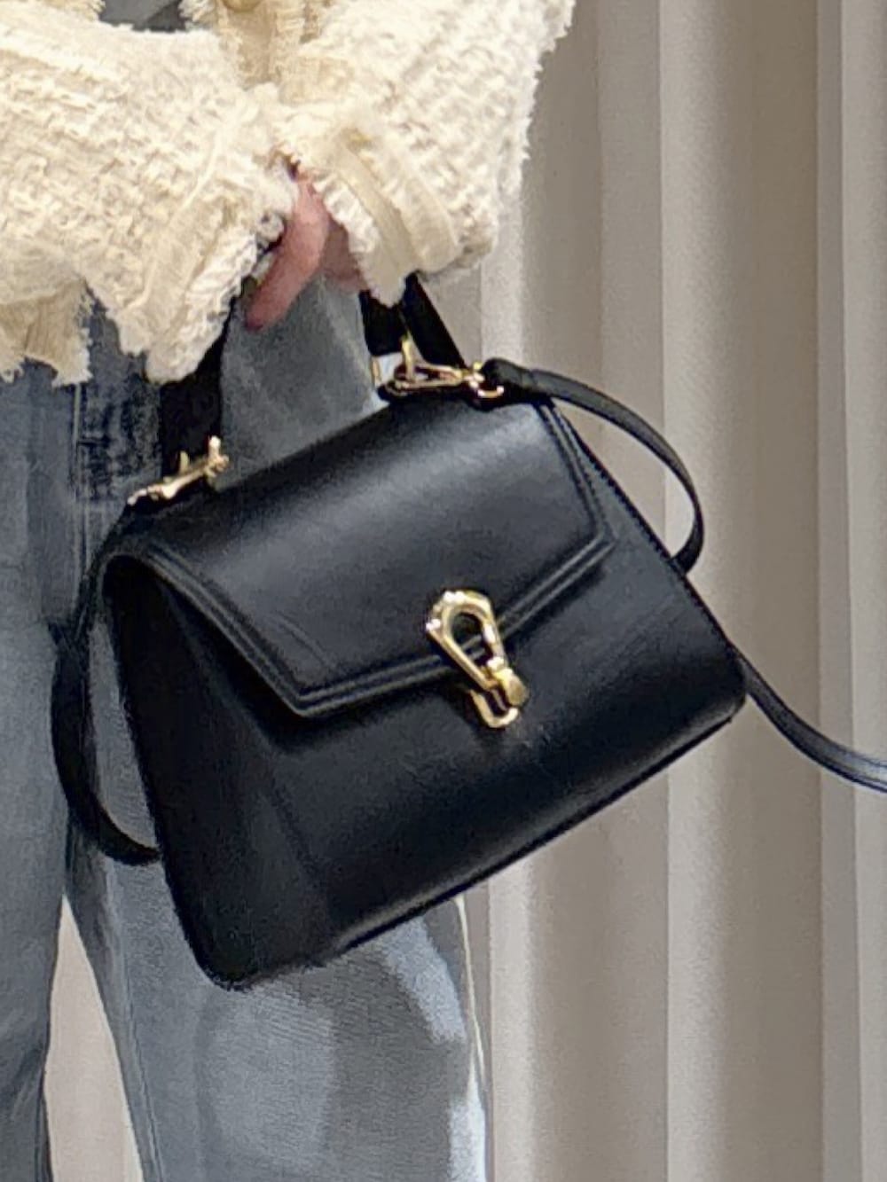 ブラック系のトートバッグ、ブルー系のデニムパンツ、ブラック系のパンプスを着用したレディースの冬コーディネートの3枚目の写真