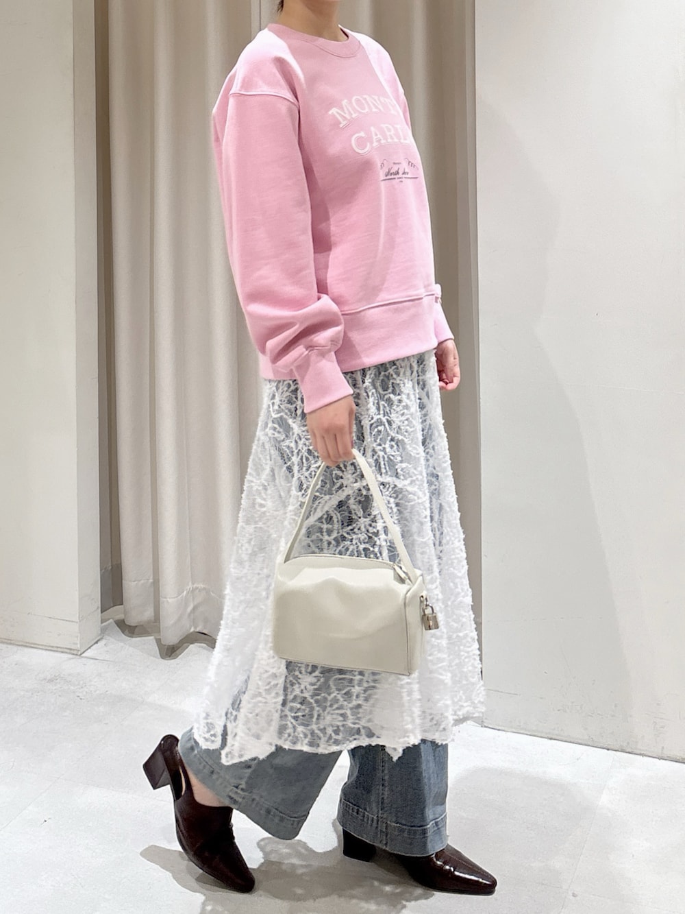 ピンク系のスウェット、ホワイト系のスカート、ブルー系のデニムパンツを着用したレディースの冬コーディネートの2枚目の写真