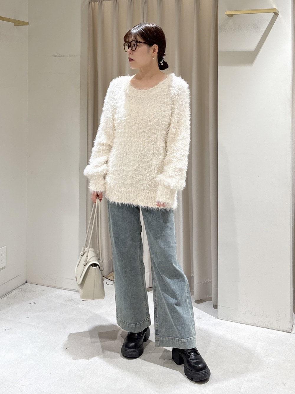 ホワイト系のニット/セーター、ブルー系のデニムパンツ、ホワイト系のショルダーバッグを着用したレディースの冬コーディネートの2枚目の写真