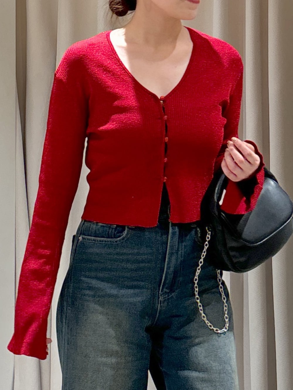 レッド系のニット/セーター、ブルー系のデニムパンツ、ブラック系のショルダーバッグを着用したレディースの秋コーディネートの4枚目の写真