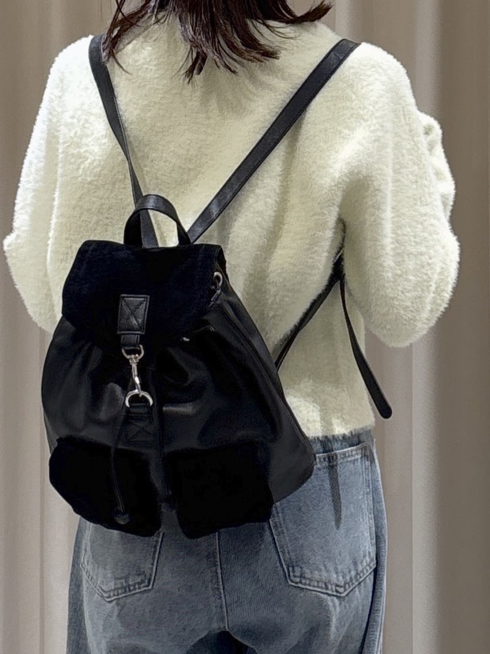 イエロー系のニット/セーター、ブルー系のデニムパンツ、ブラック系のバックパック/リュックを着用したレディースの秋コーディネートの4枚目の写真