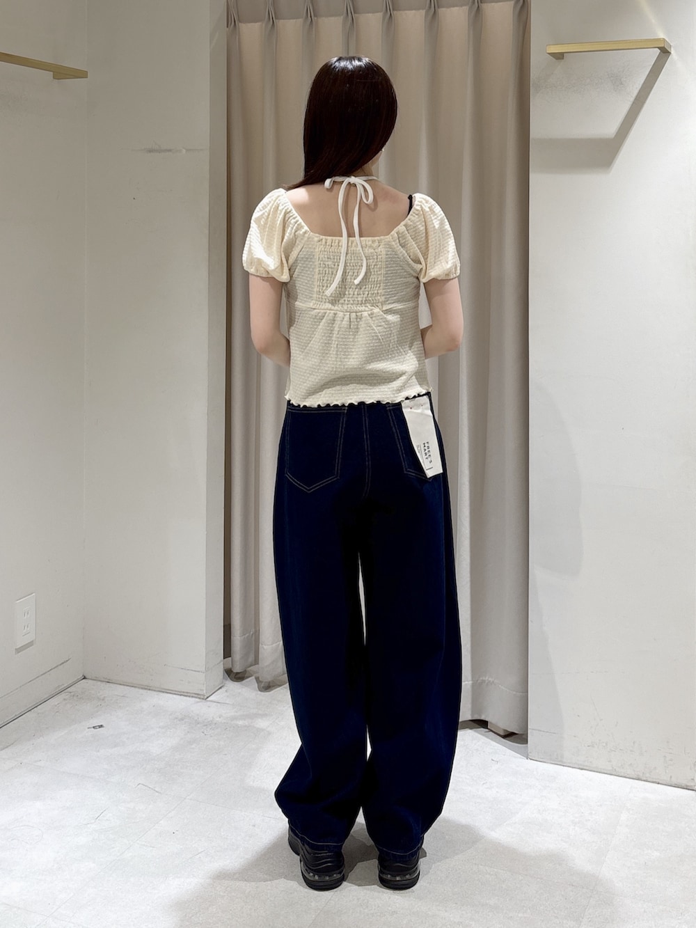 ブルー系のデニムパンツ、ブラック系のハンドバッグ、ブラウン系のサンダルを着用したレディースの夏コーディネートの3枚目の写真
