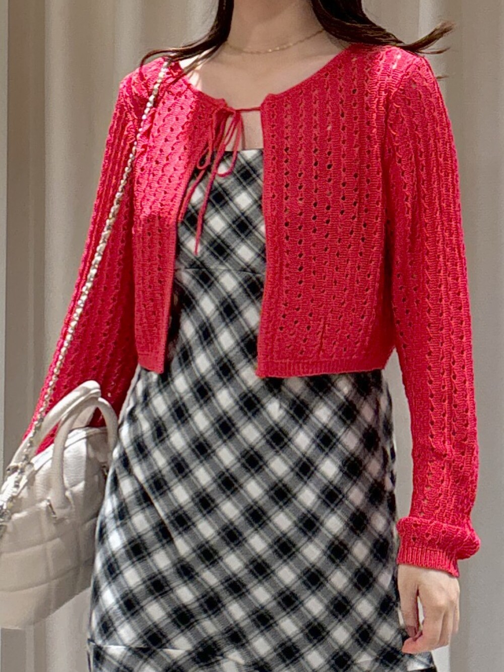 レッド系のカーディガン/ボレロ、ブラック系のワンピース、ホワイト系のトートバッグを着用したレディースの夏コーディネートの3枚目の写真