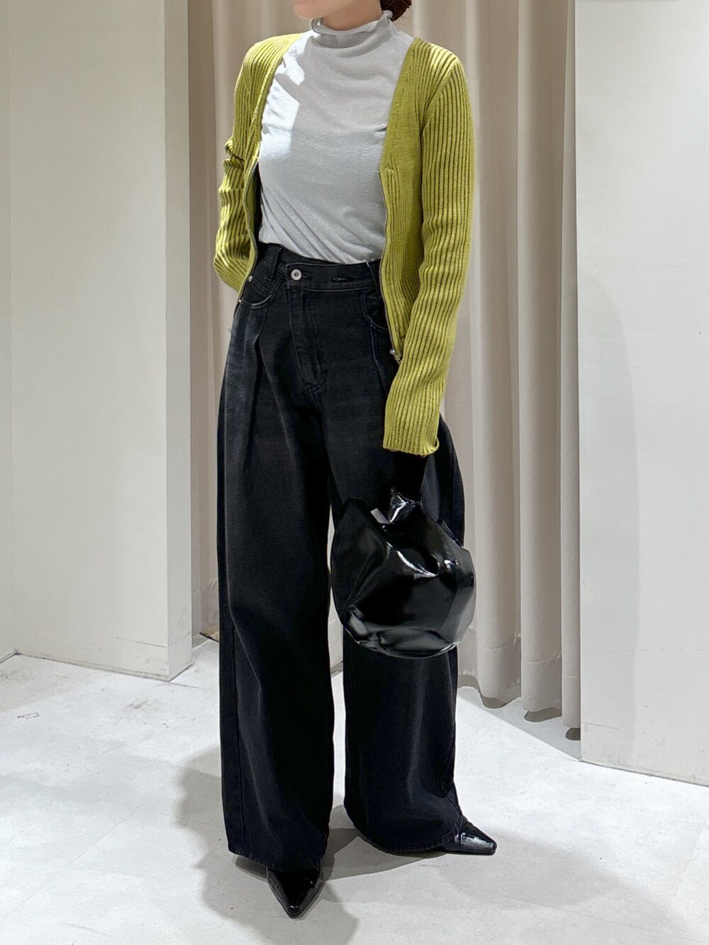 グリーン系のニット/セーター、グレー系のTシャツ/カットソー、ブラック系のハンドバッグを着用したレディースの秋コーディネートの5枚目の写真