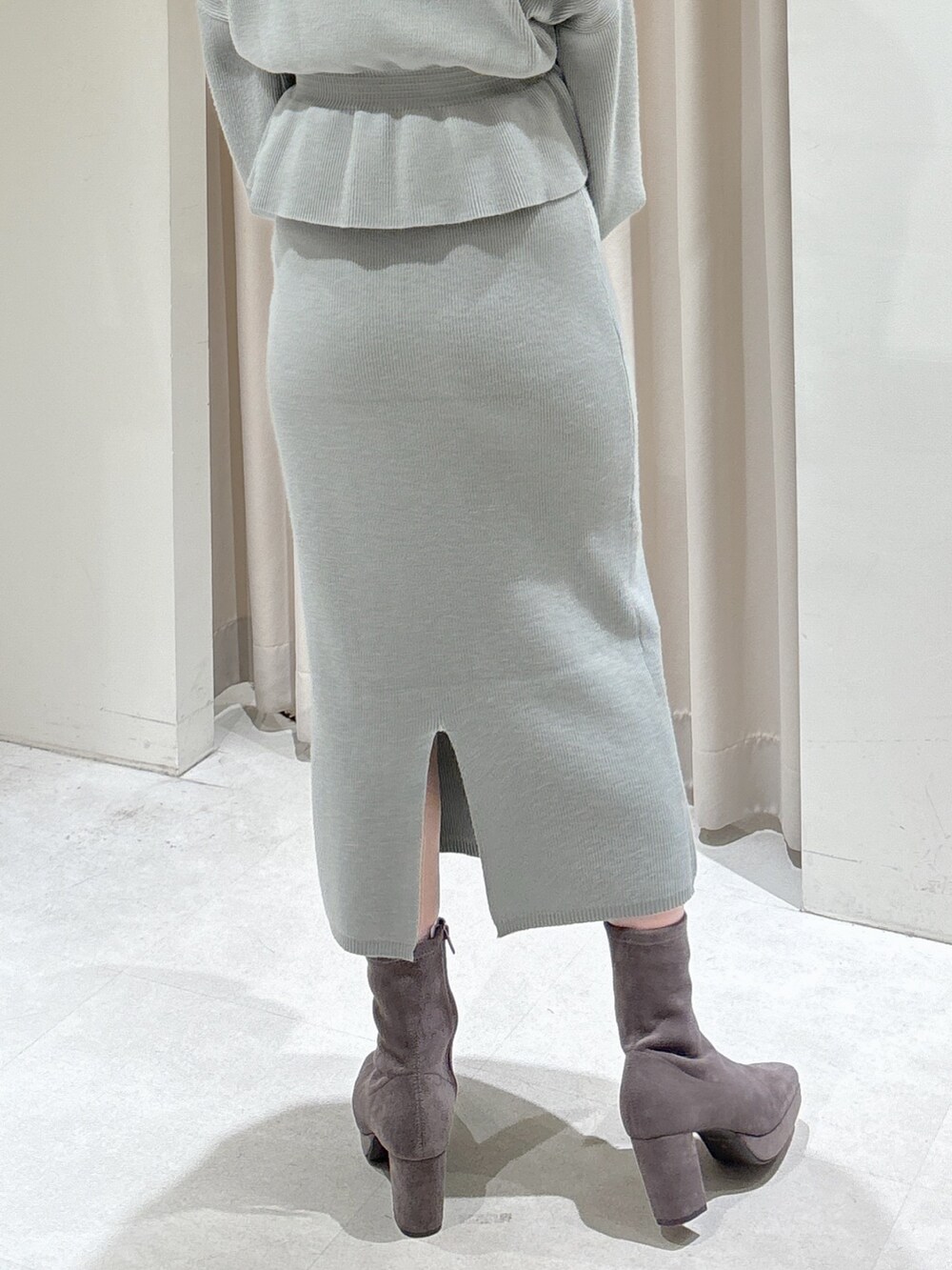 グリーン系のワンピース、ブラック系のショルダーバッグ、グレー系のブーツを着用したレディースの冬コーディネートの5枚目の写真