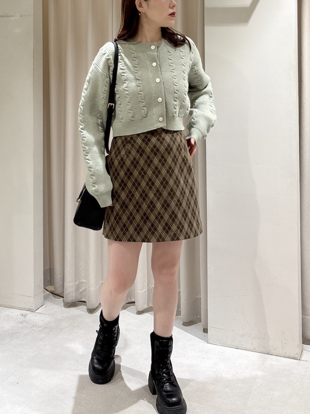 グリーン系のワンピース、ブラウン系のスカート、ブラック系のトートバッグを着用したレディースの冬コーディネートの7枚目の写真