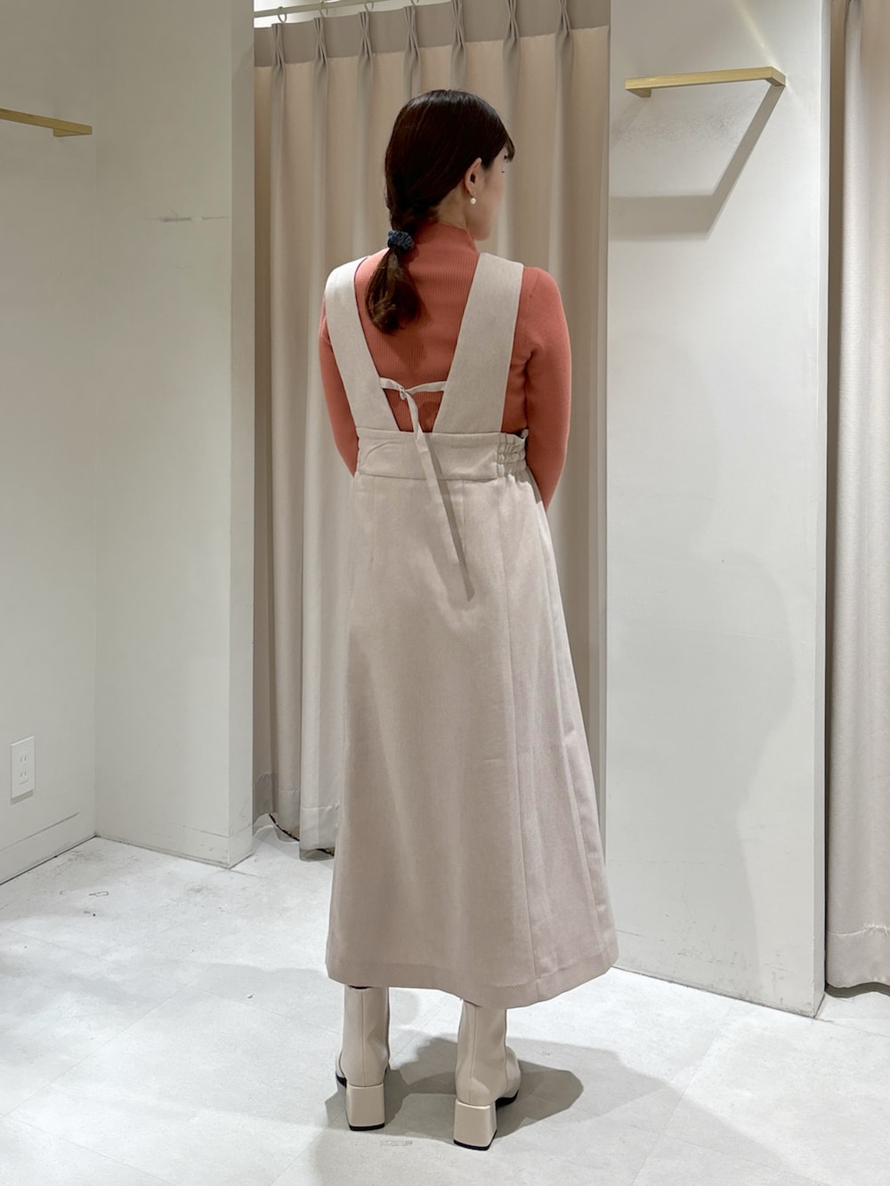 ピンク系のニット/セーター、ベージュ系のジャンパースカート、ブラック系のショルダーバッグを着用したレディースの冬コーディネートの3枚目の写真