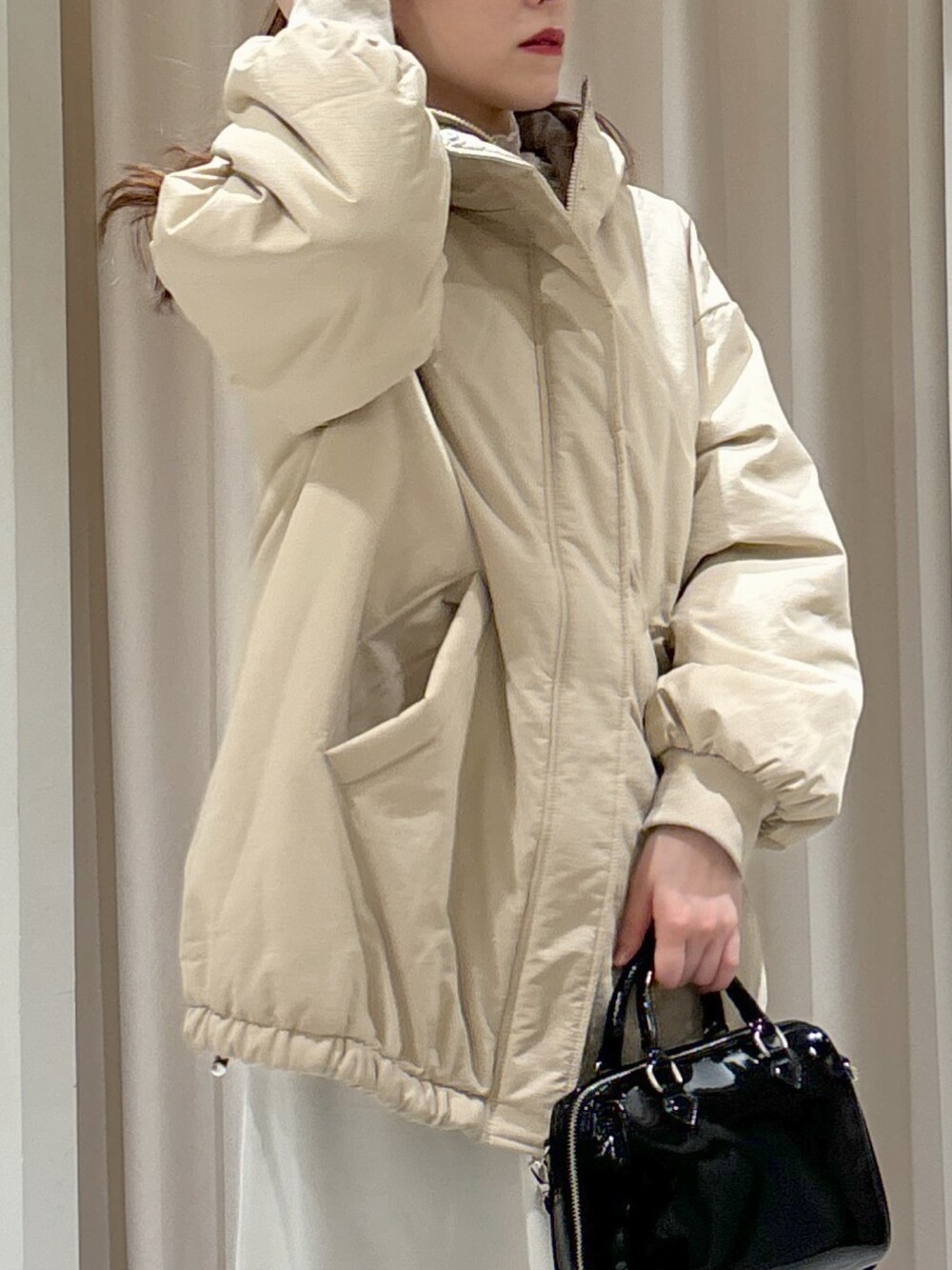 ベージュ系のブルゾン、ブラック系のショルダーバッグ、ホワイト系のスカートを着用したレディースの冬コーディネートの5枚目の写真