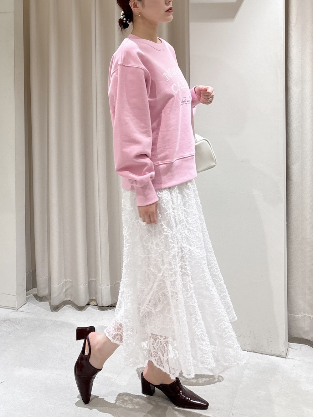 ピンク系のスウェット、ホワイト系のスカート、ホワイト系のハンドバッグを着用したレディースの冬コーディネートの2枚目の写真