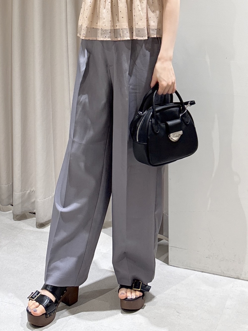 ピンク系のシャツ/ブラウス、ブラック系のハンドバッグ、グレー系のスラックスを着用したレディースの夏コーディネートの5枚目の写真