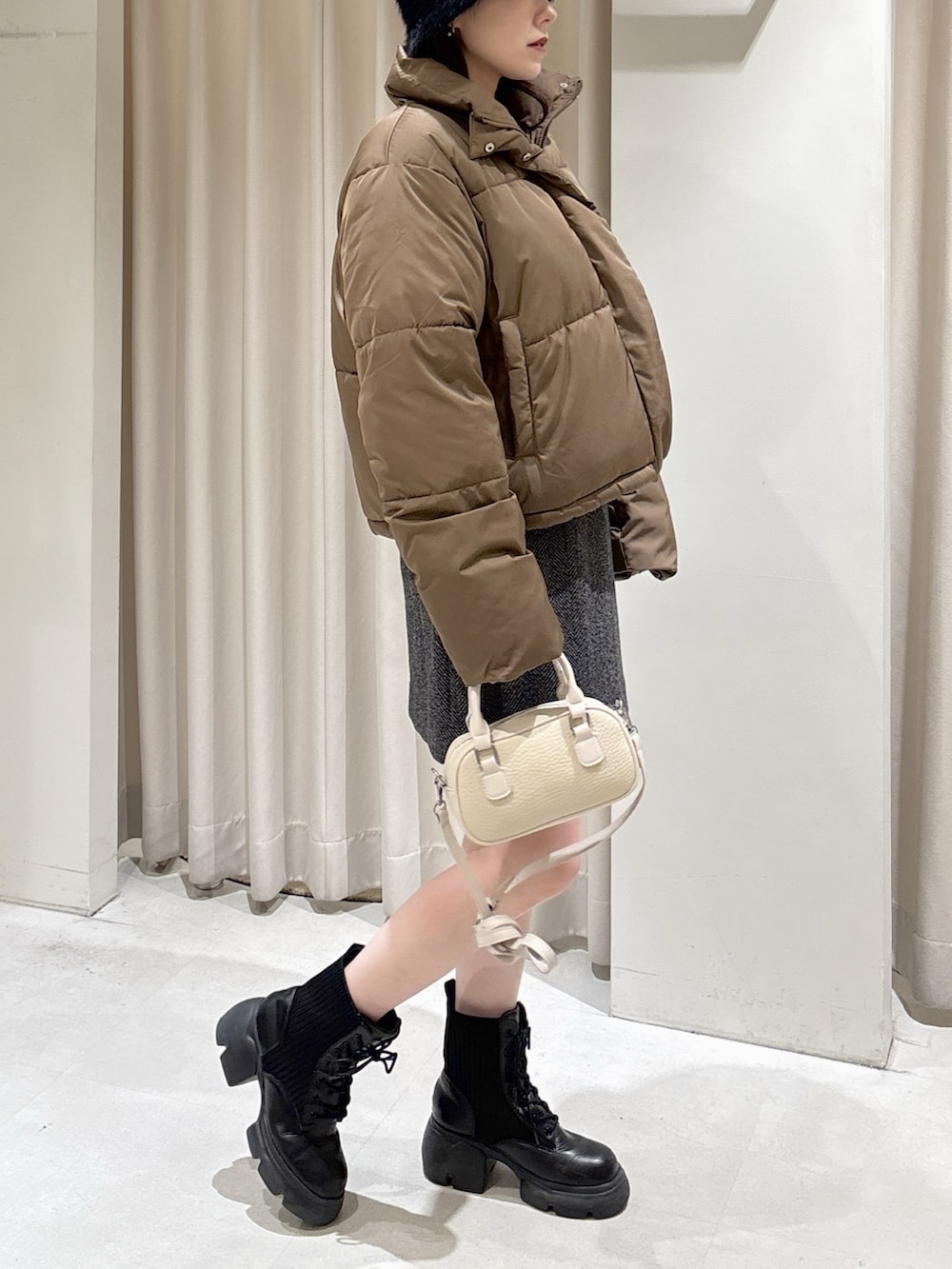 ブラウン系のブルゾン、ブラック系のスカート、ホワイト系のボストンバッグを着用したレディースの冬コーディネートの2枚目の写真