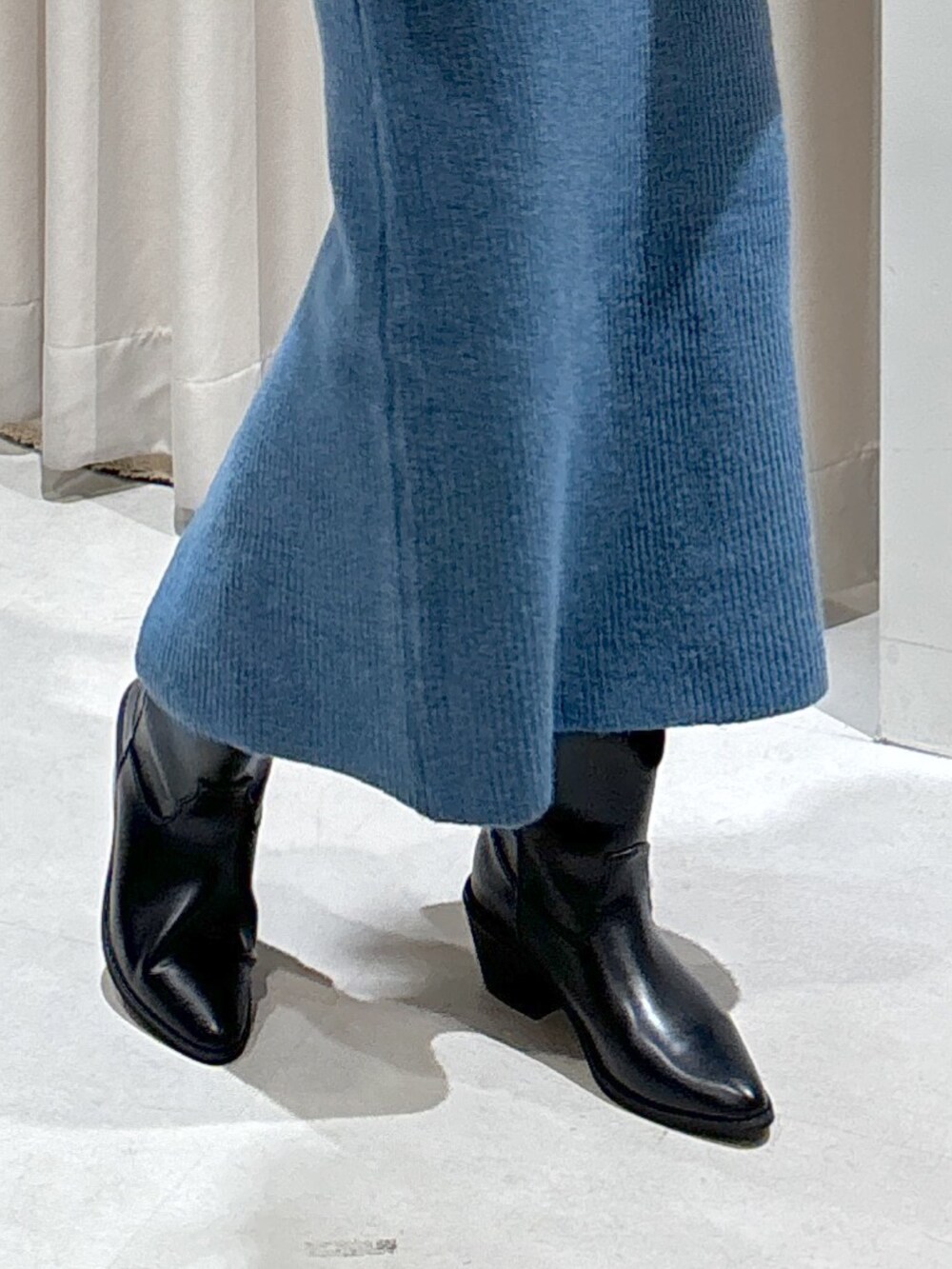 ブルー系のワンピース、ホワイト系のトートバッグ、ブラック系のブーツを着用したレディースの秋コーディネートの4枚目の写真