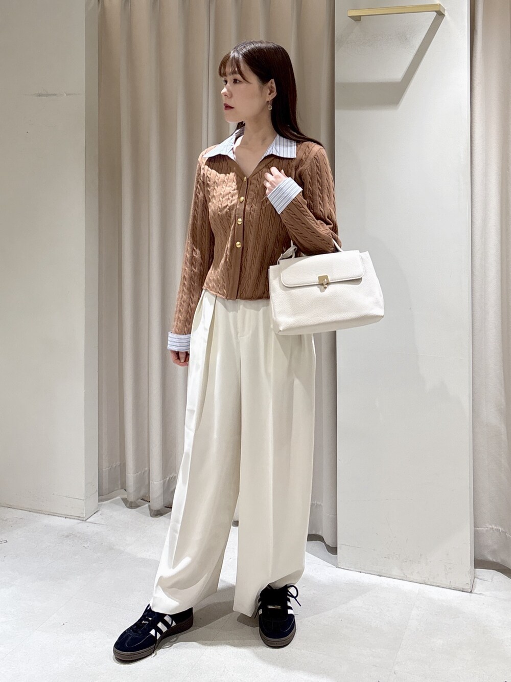 ホワイト系のトレンチコート、ベージュ系のニット/セーター、ブラック系のスニーカーを着用したレディースの冬コーディネートの6枚目の写真