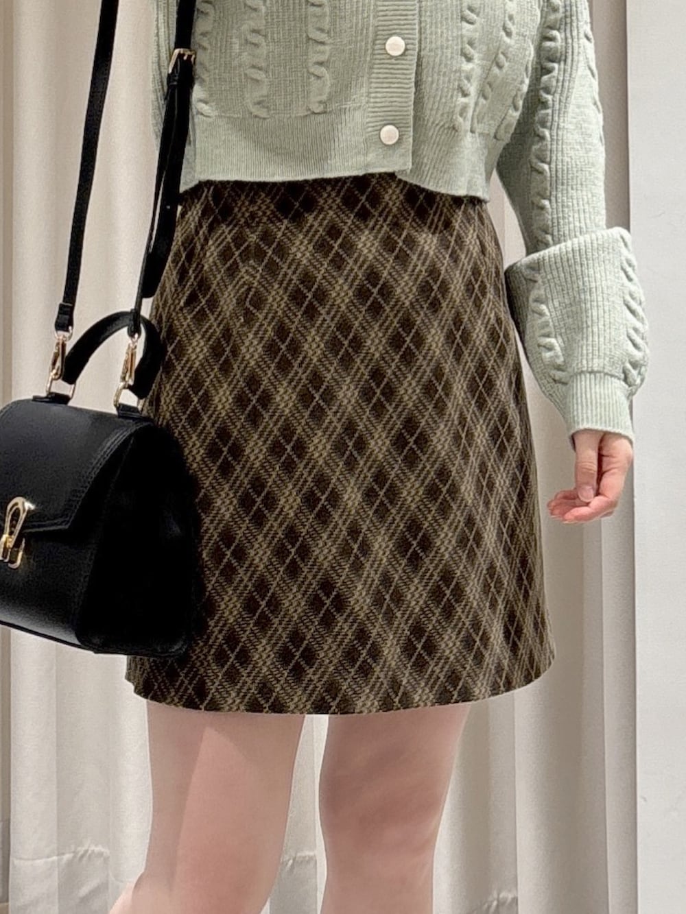 グリーン系のワンピース、ブラウン系のスカート、ブラック系のトートバッグを着用したレディースの冬コーディネートの4枚目の写真